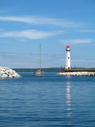 A sailboat enters the St. Ignace harbor with Mackinac Island in the distance beyond. 